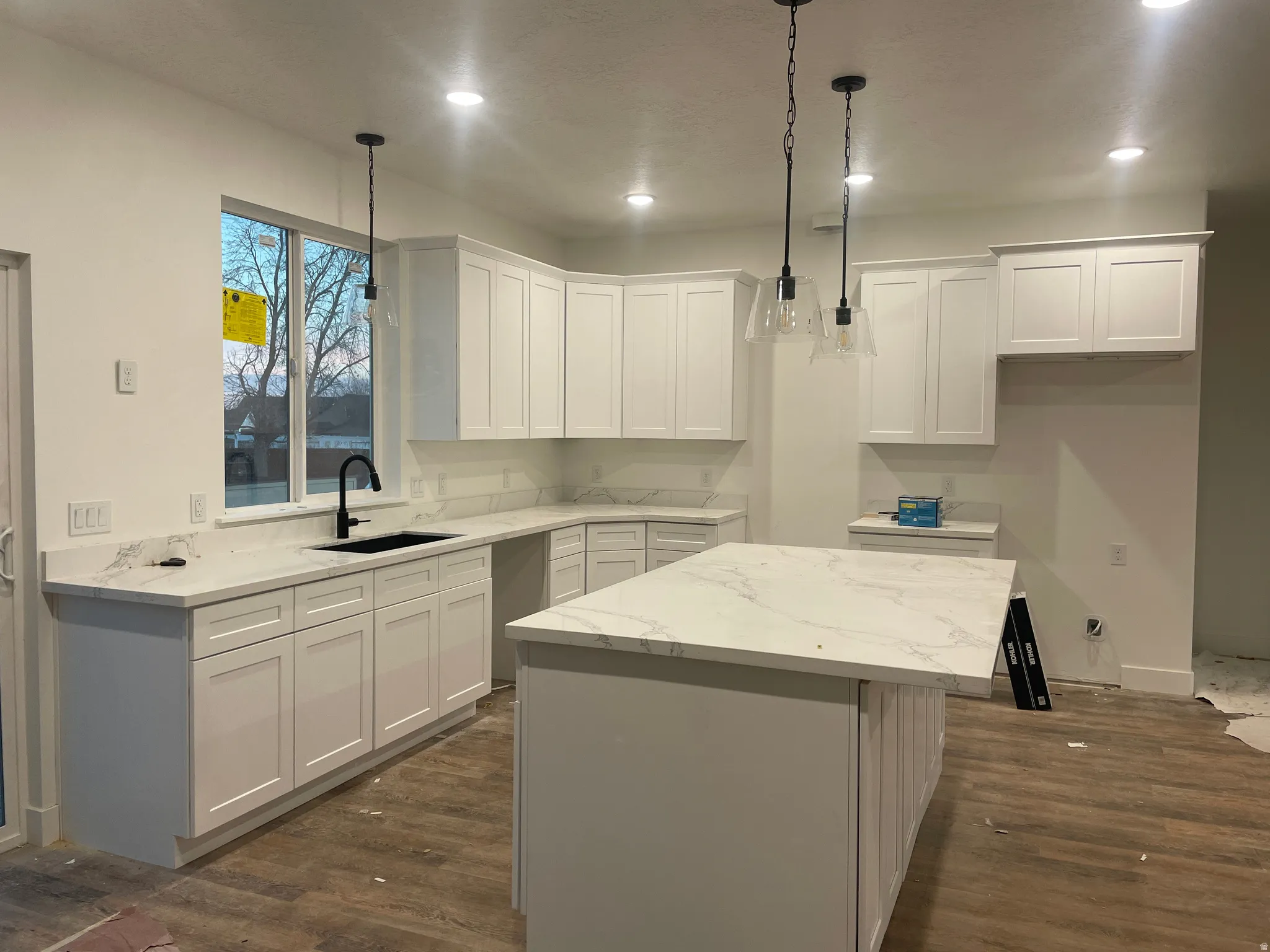 Kitchen with a center island, light stone countertops, white cabinetry, recessed lighting, and dark wood-style floors