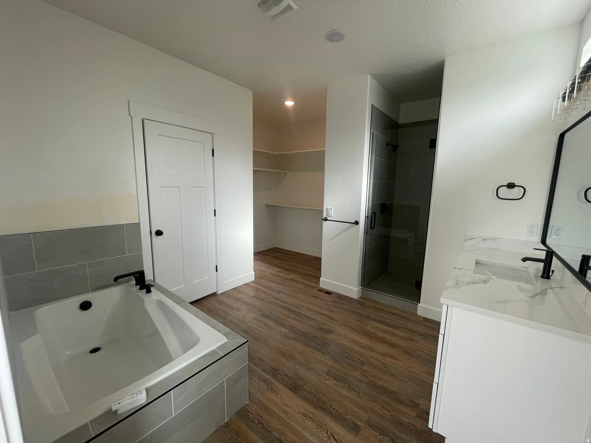 Full bathroom featuring vanity, a stall shower, a garden tub, dark wood finished floors, and recessed lighting