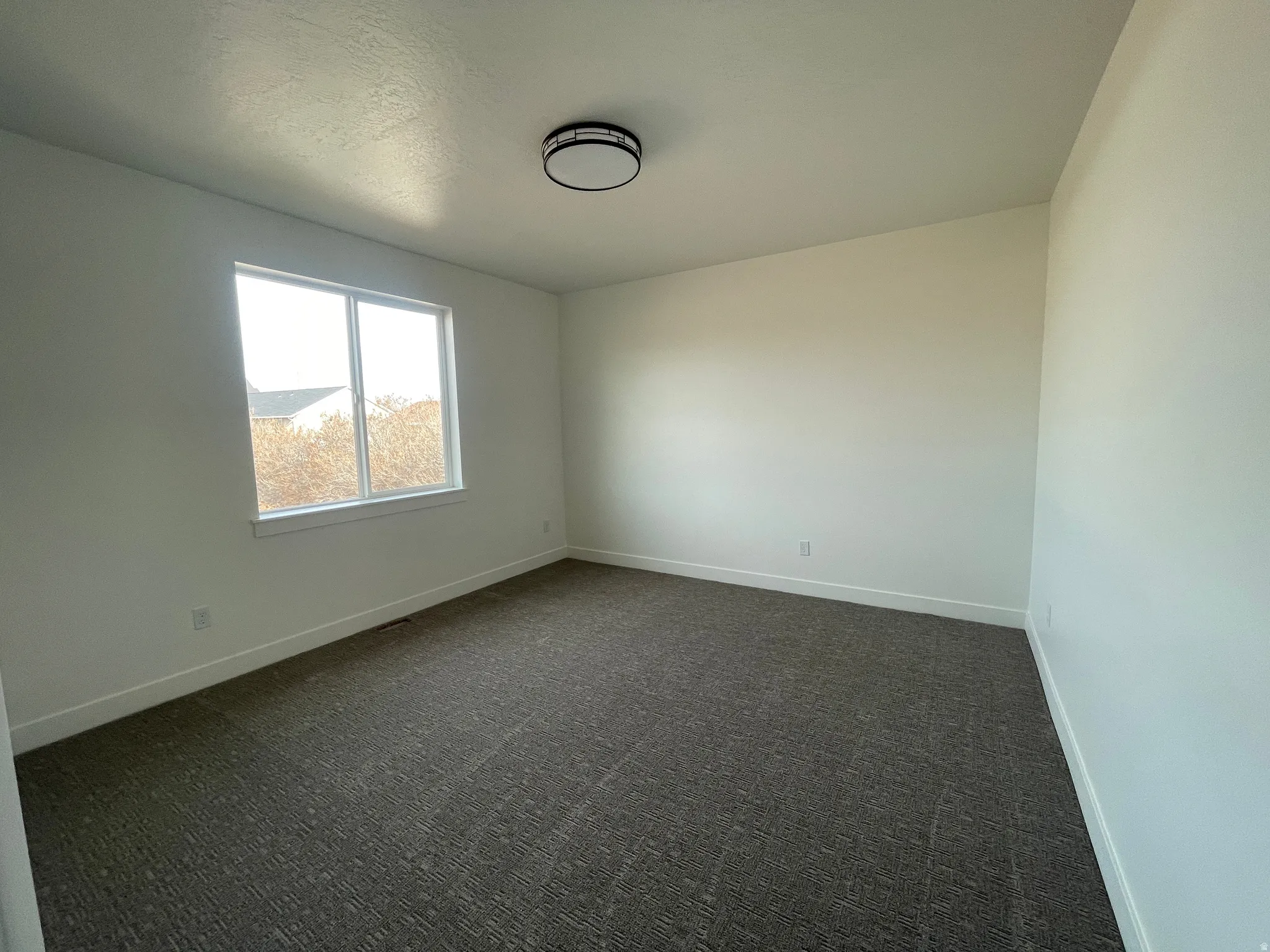 Unfurnished room featuring dark colored carpet and baseboards
