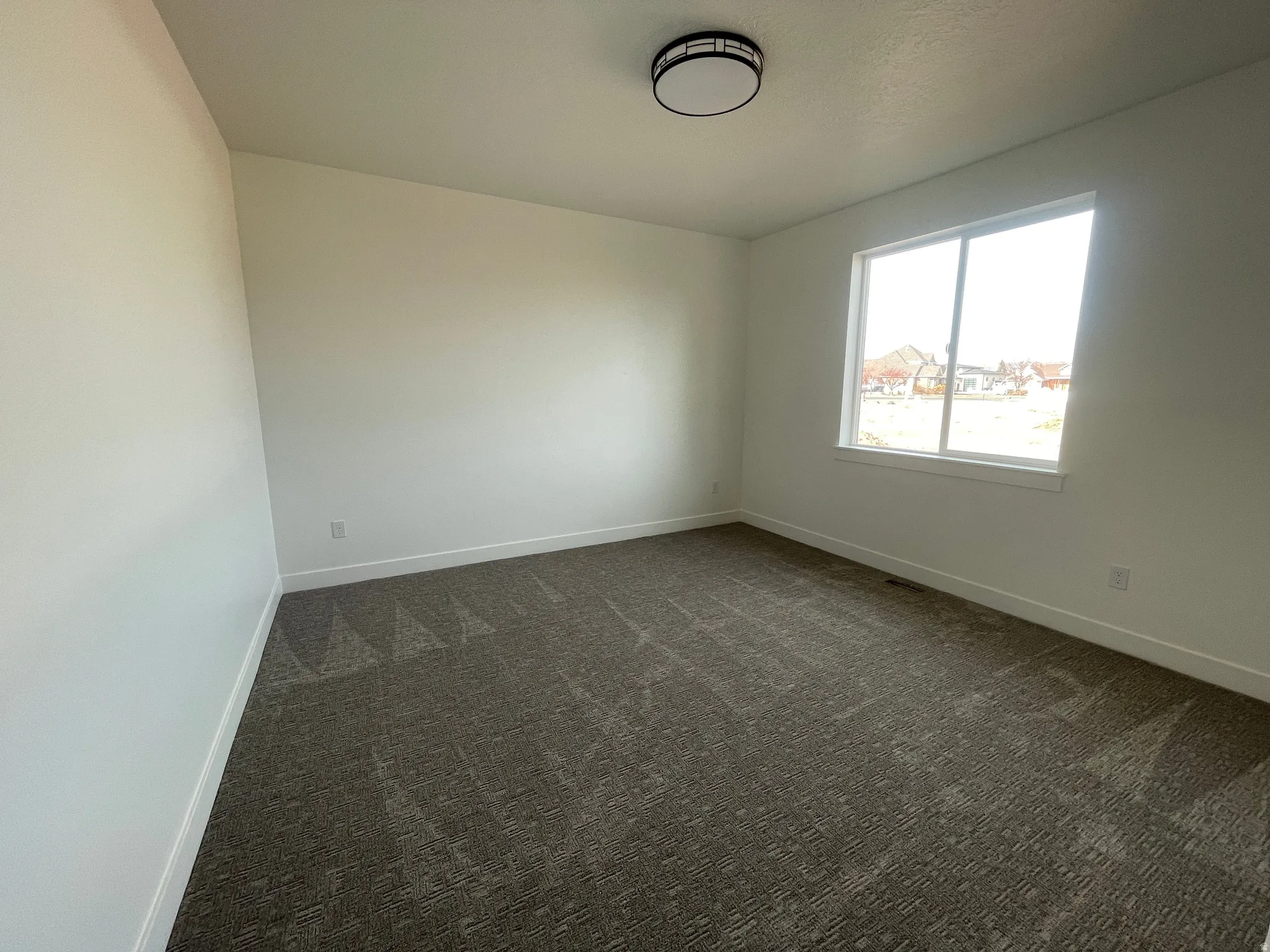 Spare room with dark carpet and baseboards