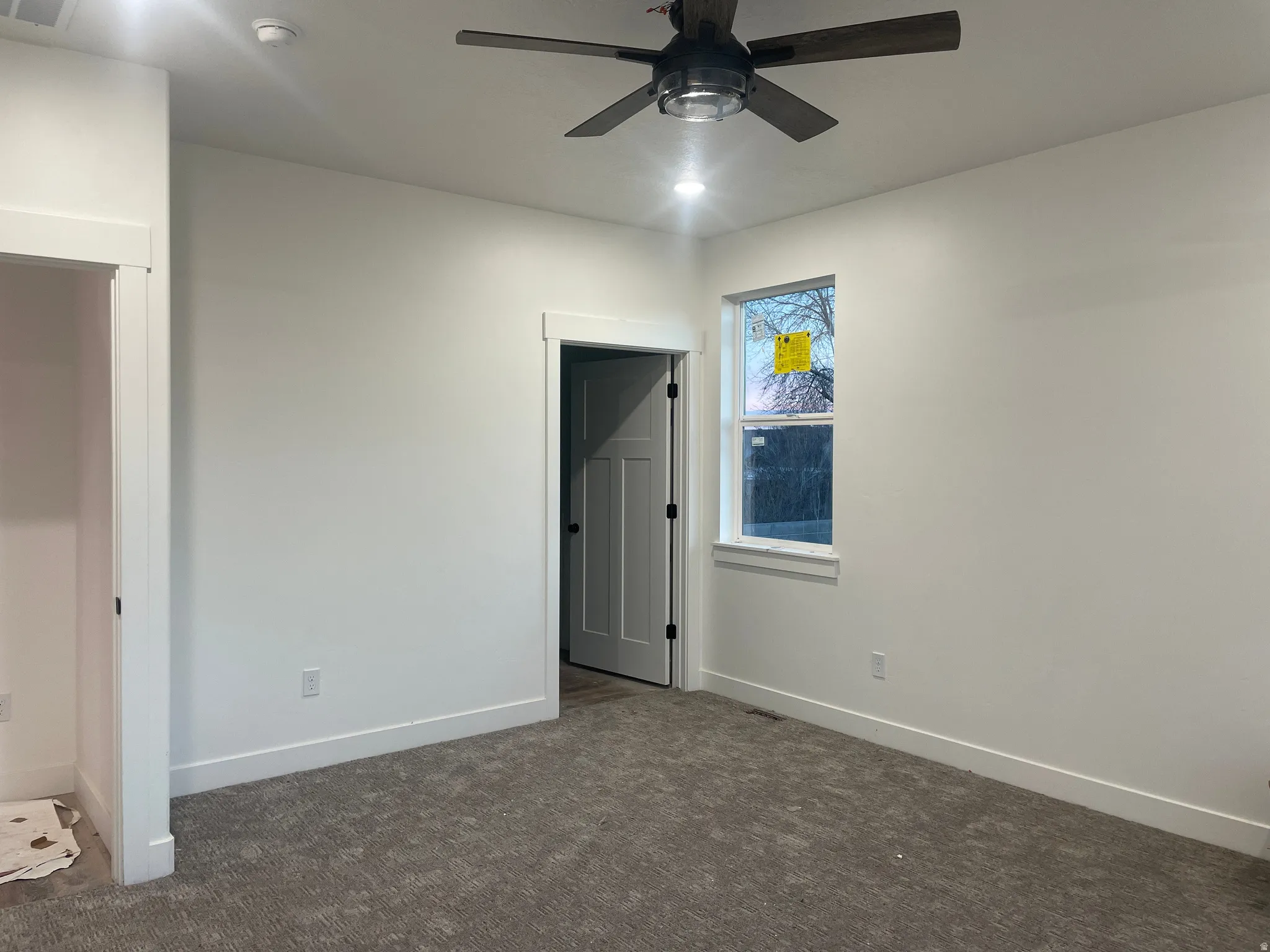 Unfurnished bedroom featuring dark colored carpet and a ceiling fan