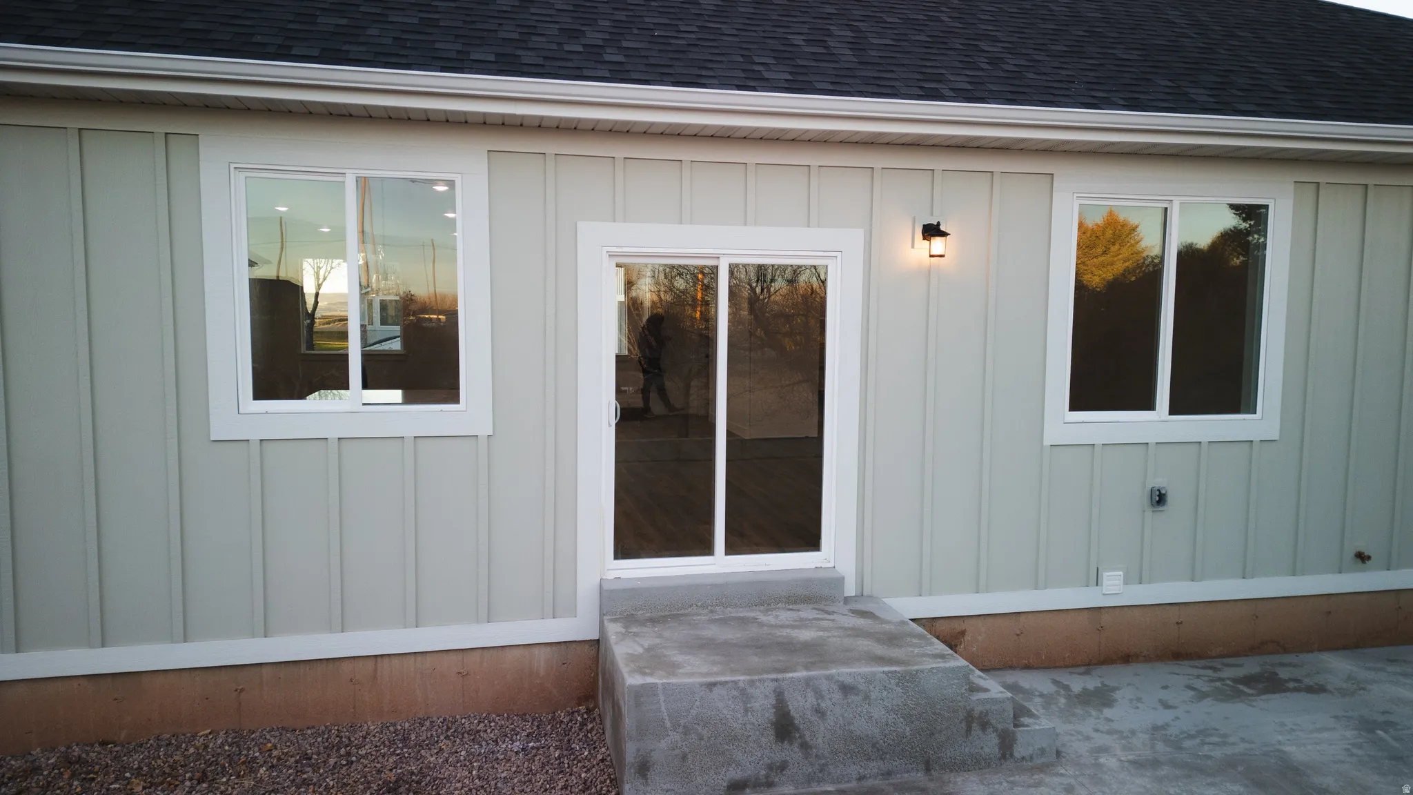 Doorway to property featuring a shingled roof and board and batten siding