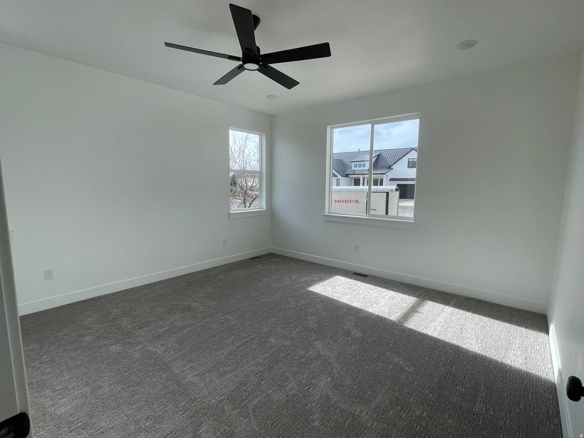 Empty room with dark carpet and a ceiling fan
