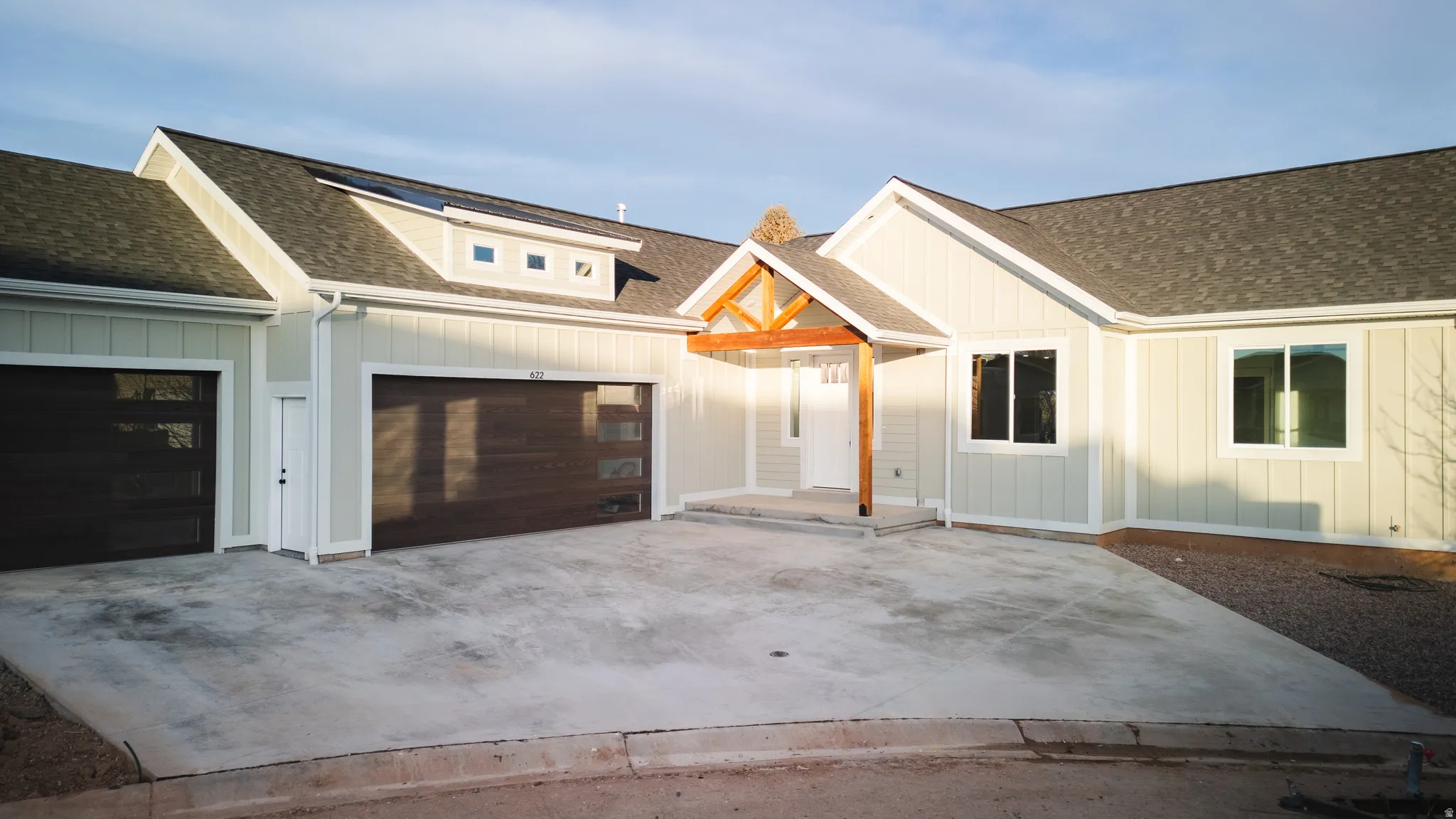 Modern inspired farmhouse with a shingled roof, board and batten siding, and driveway