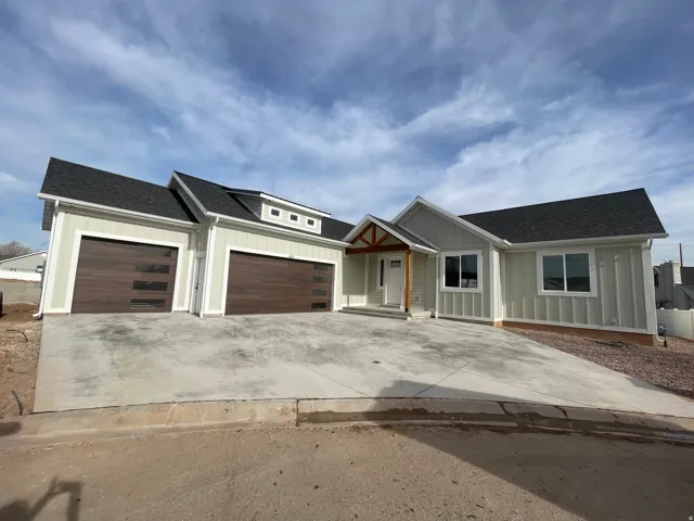 View of front facade with roof with shingles, board and batten siding, concrete driveway, and a garage