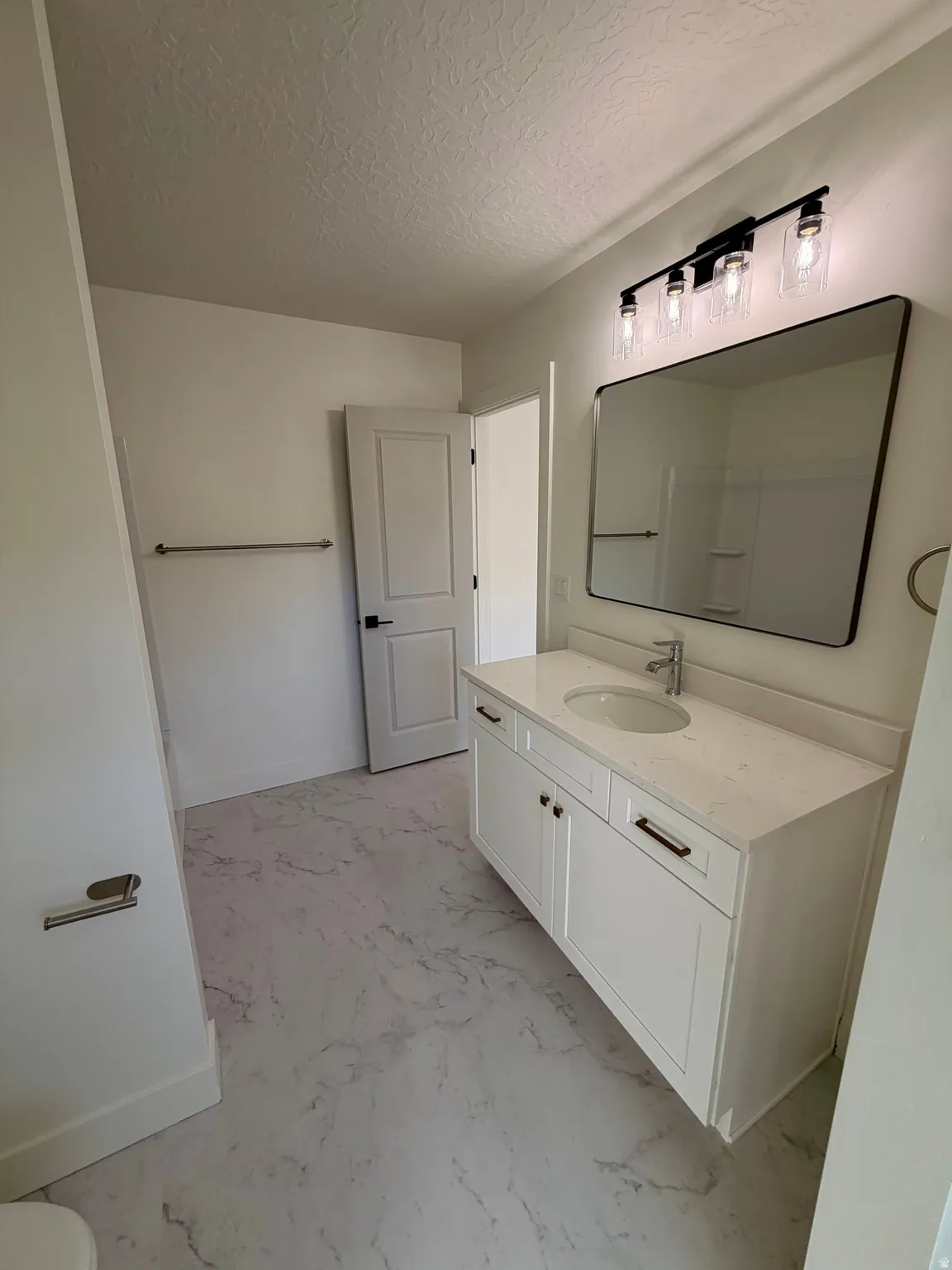 Bathroom featuring vanity, a textured ceiling, and light marble finish flooring