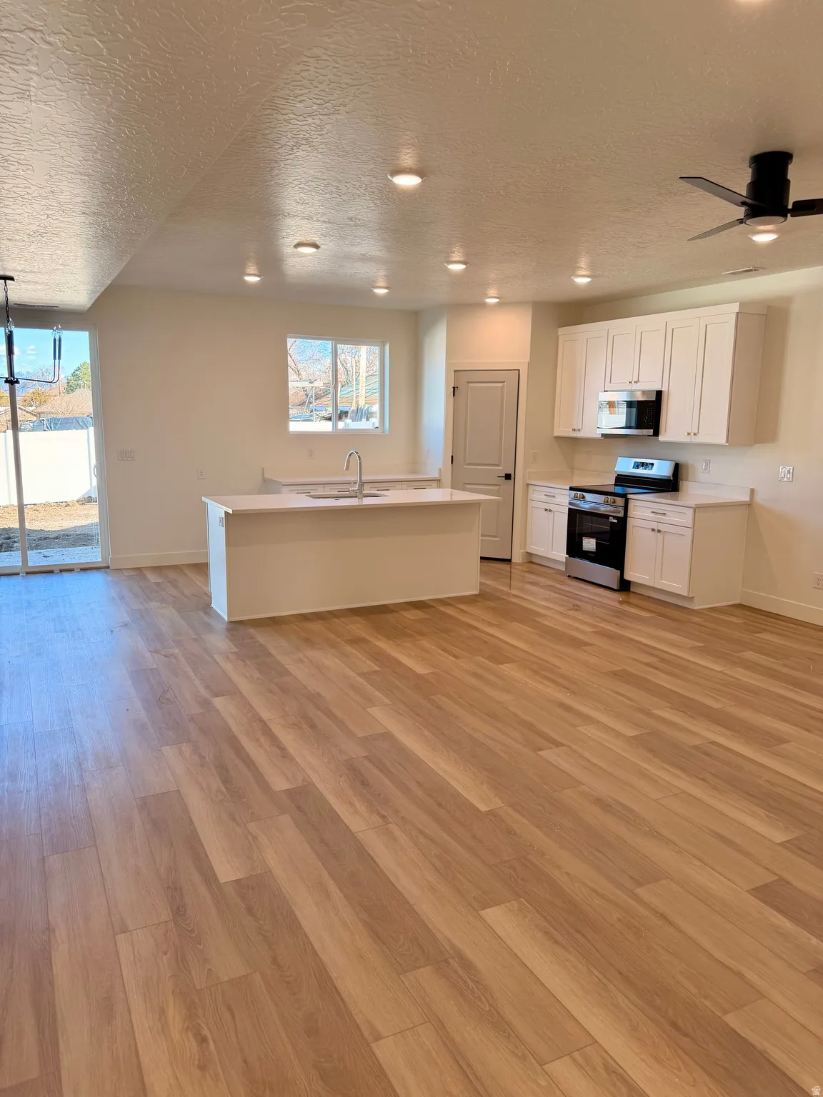 Kitchen featuring light countertops, white cabinets, a textured ceiling, stainless steel appliances, and ceiling fan