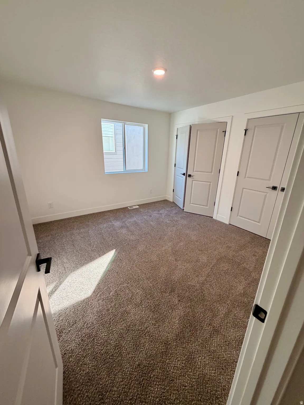 Unfurnished bedroom featuring carpet floors and multiple closets
