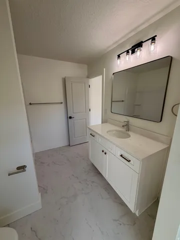 Bathroom featuring vanity, a textured ceiling, and light marble finish flooring
