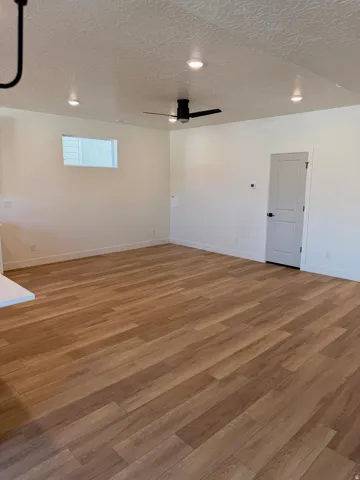 Empty room with a textured ceiling, wood finished floors, recessed lighting, and ceiling fan