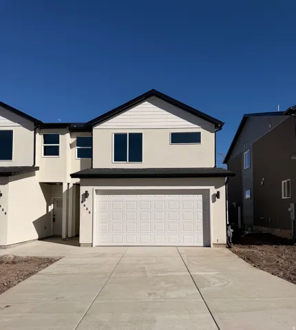 View of front of house featuring stucco siding, a garage, and driveway