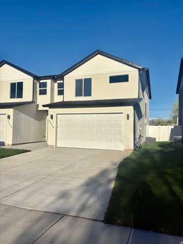 View of front of house with stucco siding, concrete driveway, and an attached garage