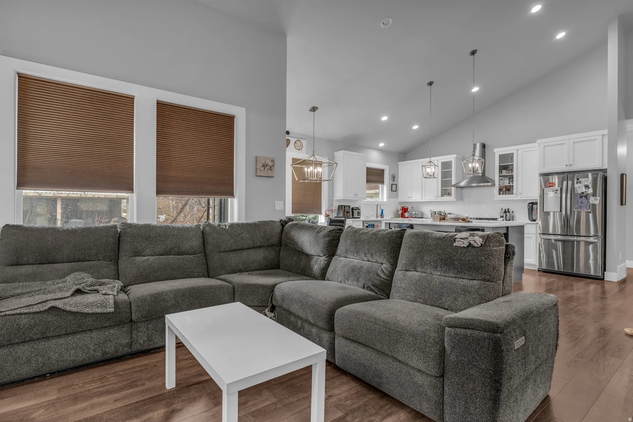 Living room with dark wood-type flooring, recessed lighting, high vaulted ceiling, and a chandelier