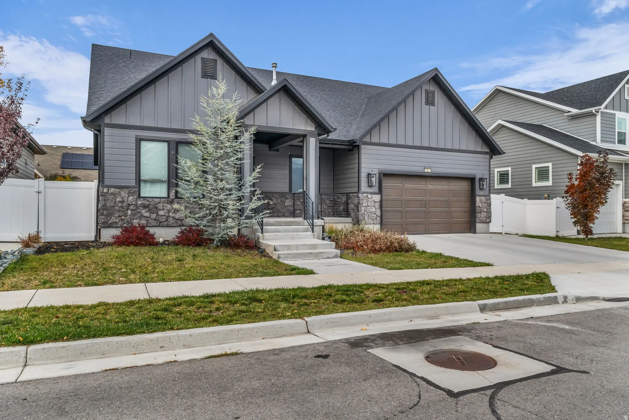 Craftsman-style home featuring stone siding, board and batten siding, and a gate