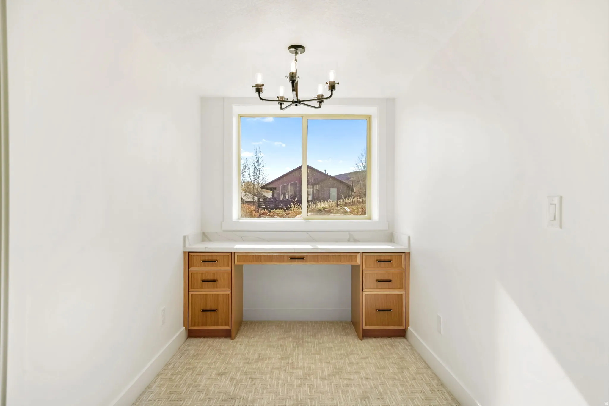 Unfurnished office featuring baseboards and a chandelier
