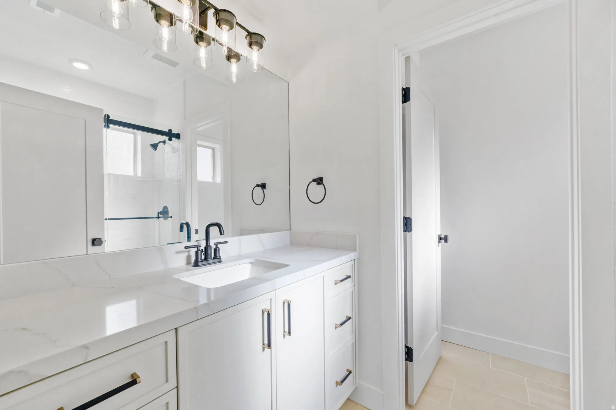 Bathroom featuring vanity, light tile patterned flooring, and a shower stall