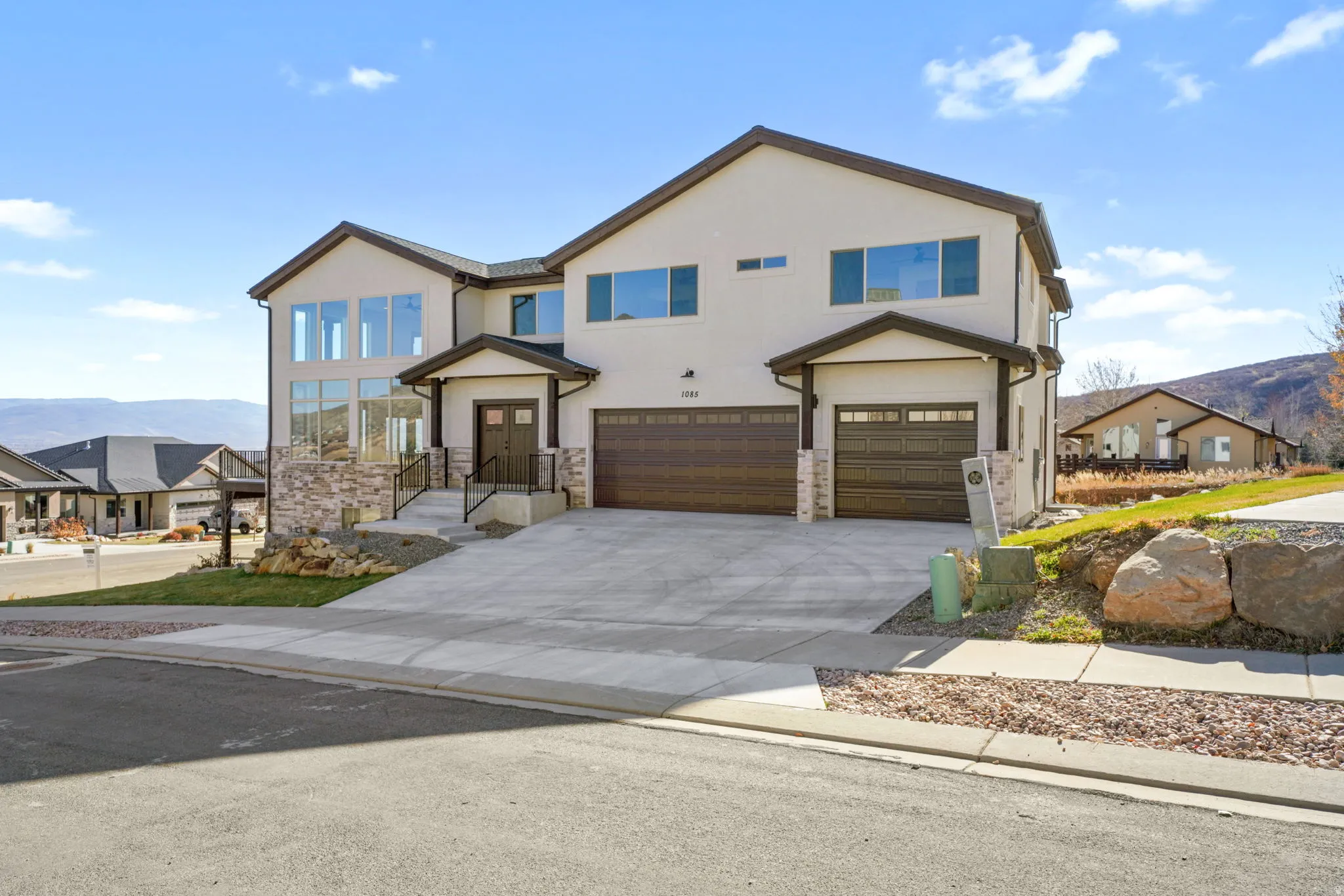 View of front of home with a mountain view, a garage, driveway, stucco siding, and stone siding