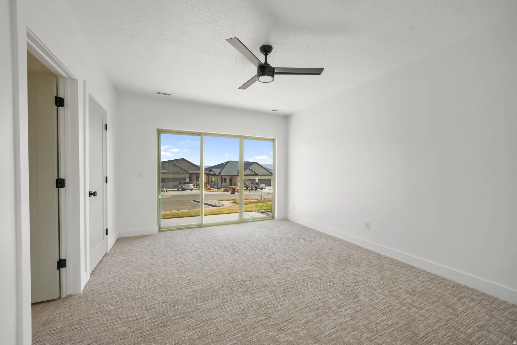 Spare room with a textured ceiling, light colored carpet, and a ceiling fan