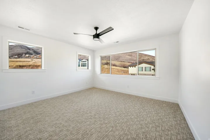 Carpeted empty room with a textured ceiling and ceiling fan
