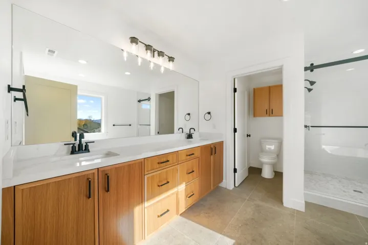 Full bath with double vanity, recessed lighting, light tile patterned flooring, and a stall shower