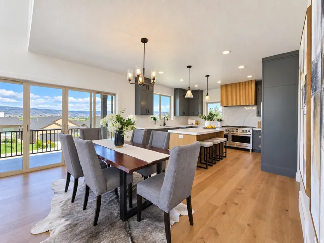 Open-concept living space featuring wood-finish flooring, a contemporary dining chandelier, and sliding glass doors to the exterior
