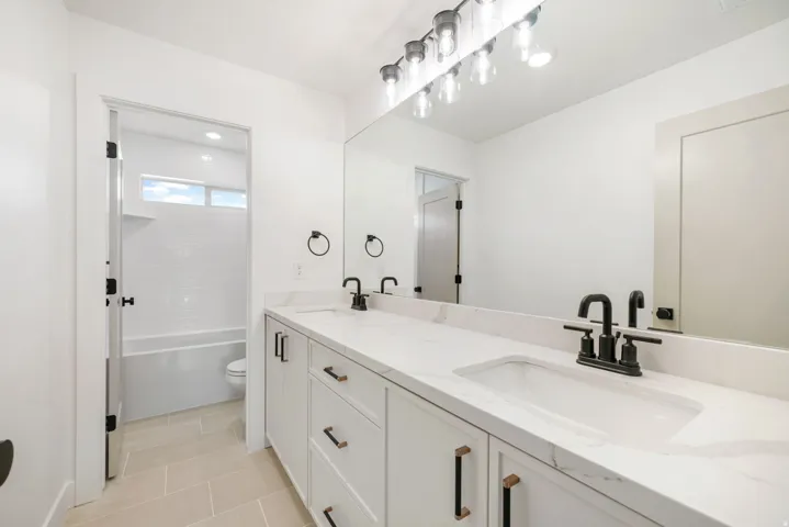 Bathroom featuring double vanity, light tile patterned floors, and bathing tub / shower combination