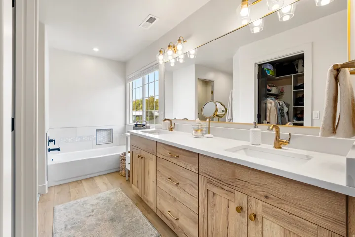 Bathroom featuring double vanity, a walk in closet, light wood-type flooring, a bath, and recessed lighting