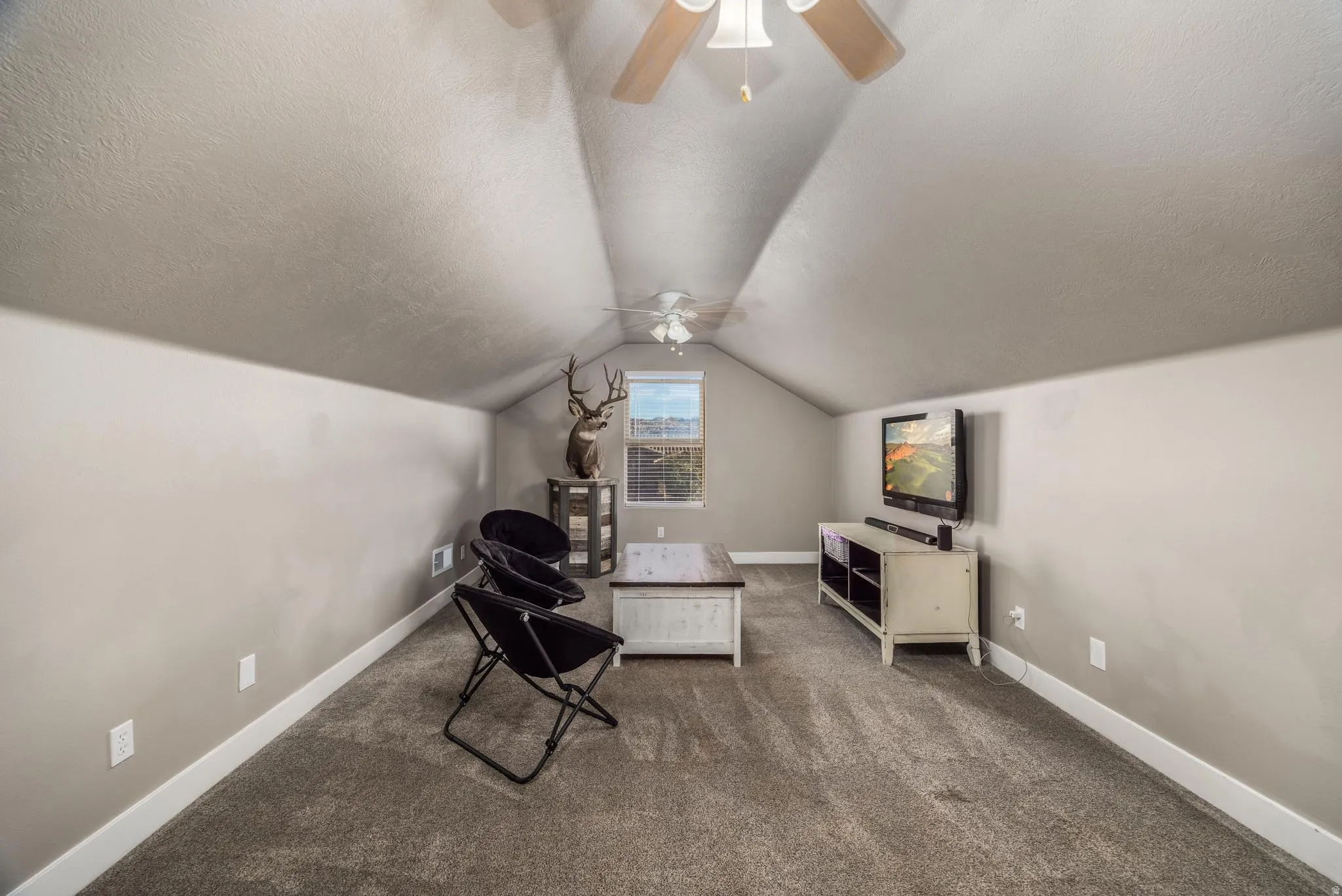 Sitting room featuring carpet flooring, a textured ceiling, vaulted ceiling, and a ceiling fan