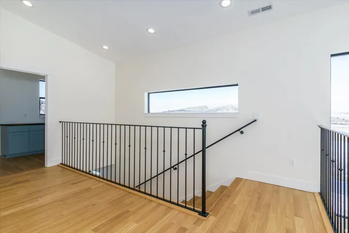 Stairs with wood finished floors, healthy amount of natural light, and recessed lighting