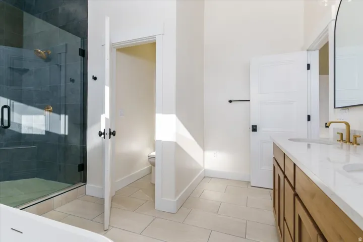 Bathroom with double vanity, a shower stall, and light tile patterned flooring