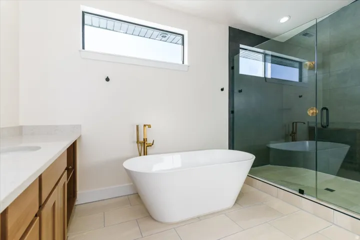 Bathroom with a freestanding tub, vanity, a stall shower, and light tile patterned floors