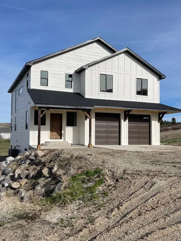 Modern farmhouse style home featuring an attached garage, covered porch, driveway, and a shingled roof