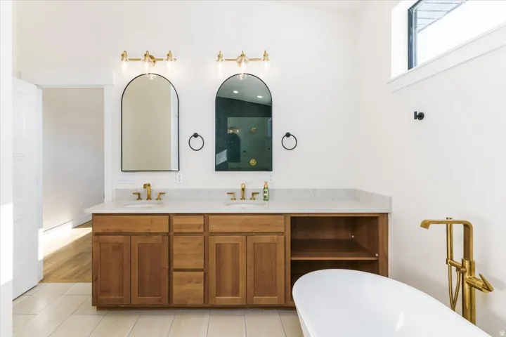Full bath featuring double vanity, a freestanding tub, and light tile patterned floors