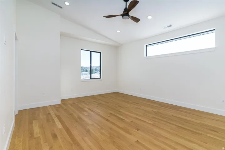 Unfurnished room featuring vaulted ceiling, light wood-style flooring, ceiling fan, and recessed lighting