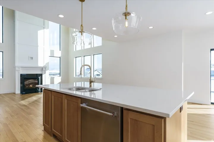 Kitchen featuring brown cabinetry, light stone countertops, plenty of natural light, light wood-style flooring, and recessed lighting