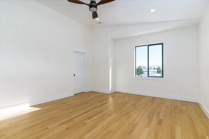 Spare room featuring vaulted ceiling, light wood-type flooring, ceiling fan, and recessed lighting