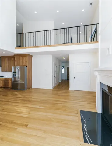Unfurnished living room with a high ceiling, recessed lighting, light wood finished floors, and a fireplace