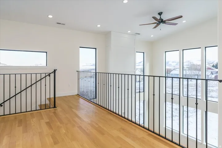 Hallway with light wood finished floors, plenty of natural light, recessed lighting, and an upstairs landing