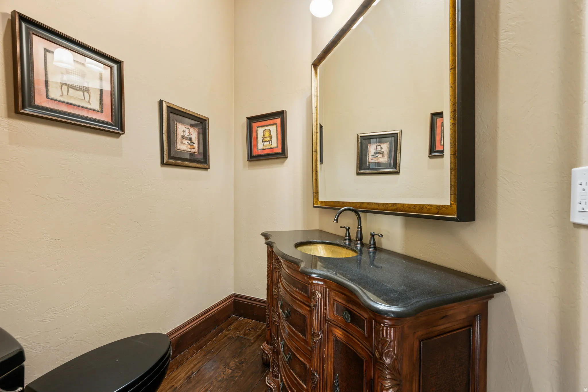 Half bathroom with vanity, dark wood-type flooring, and a textured wall