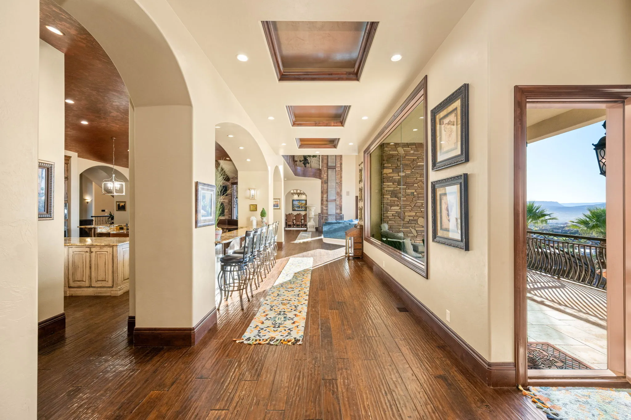 Corridor featuring dark wood-type flooring, arched walkways, a tray ceiling, and recessed lighting