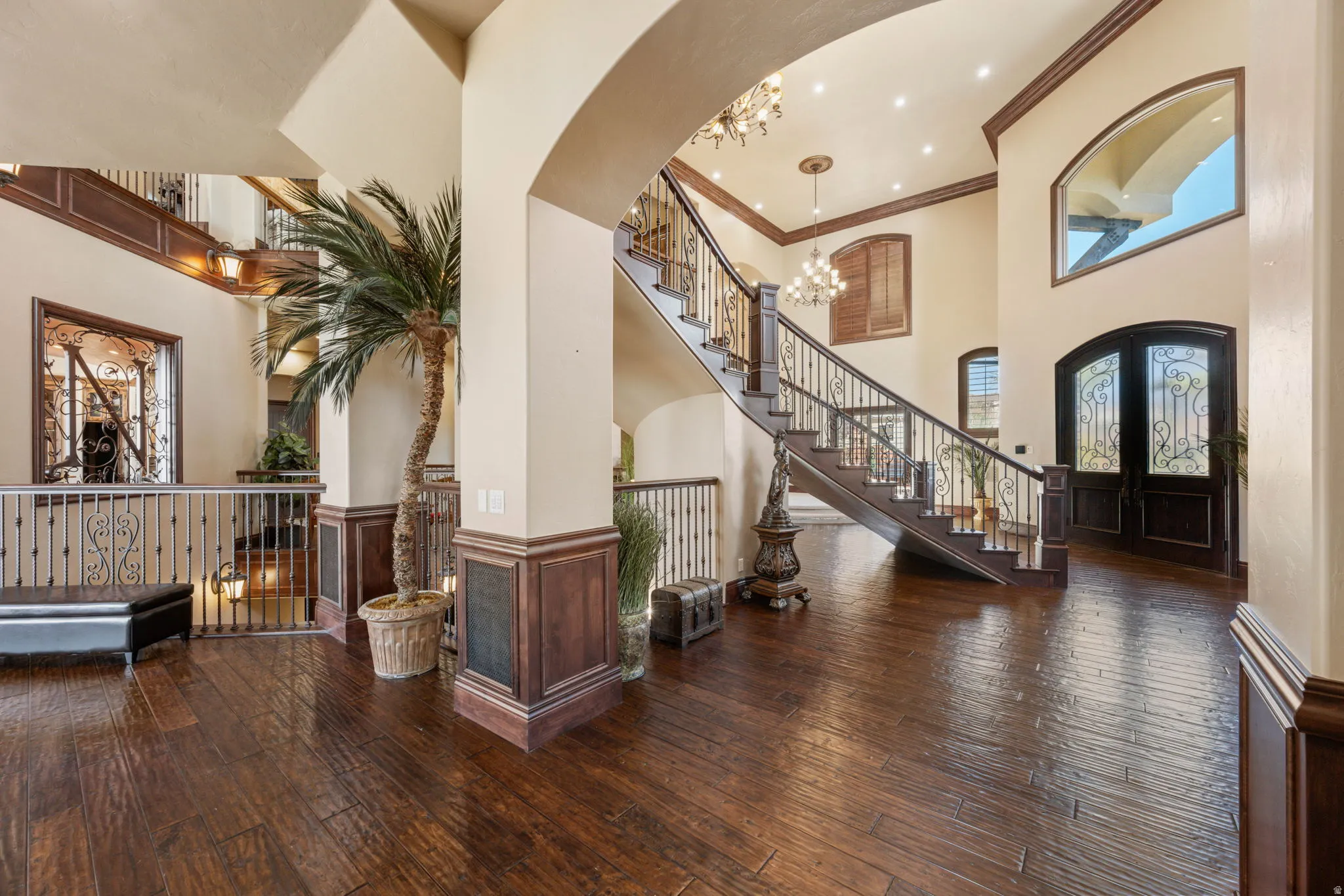 Foyer with ornamental molding, a wainscoted wall, a chandelier, a high ceiling, and dark wood finished floors