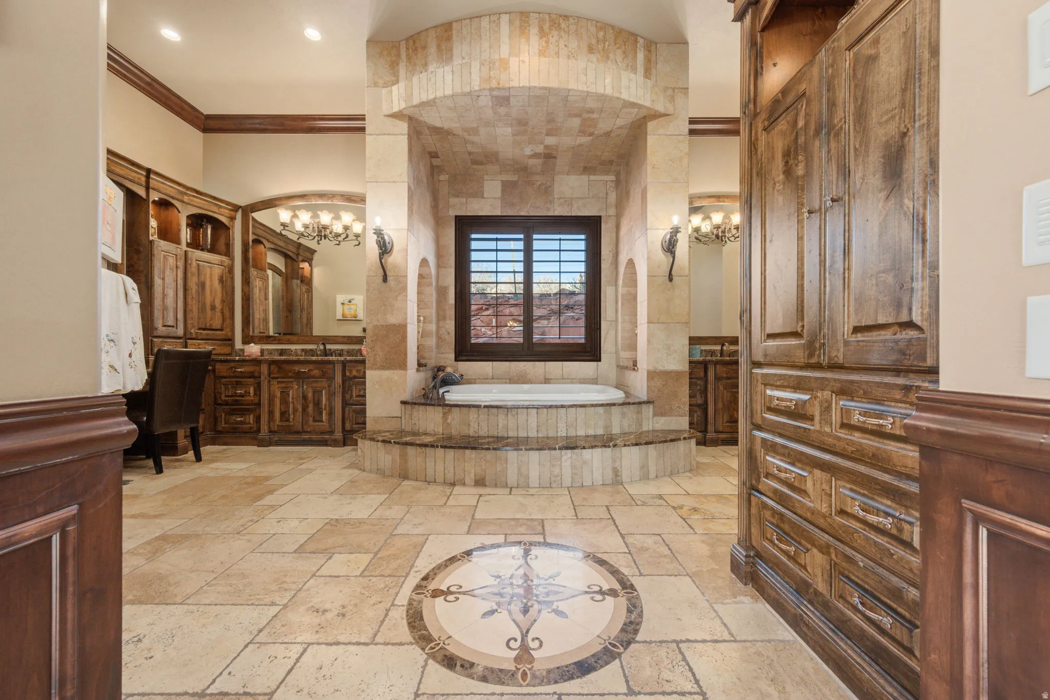 Full bathroom featuring crown molding, stone tile flooring, a chandelier, a bath, and vanity