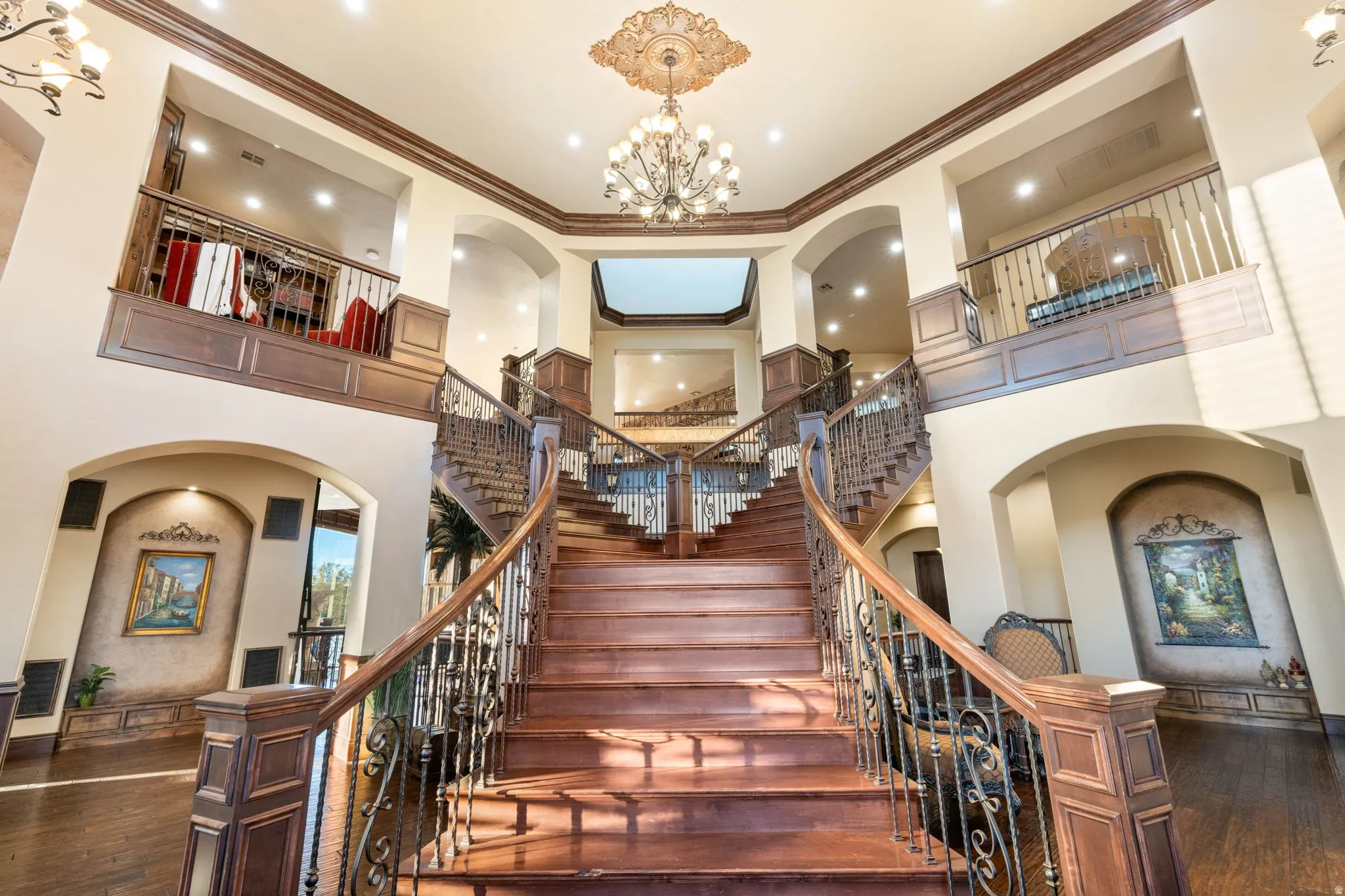 Stairs with arched walkways, a chandelier, crown molding, a towering ceiling, and hardwood / wood-style floors