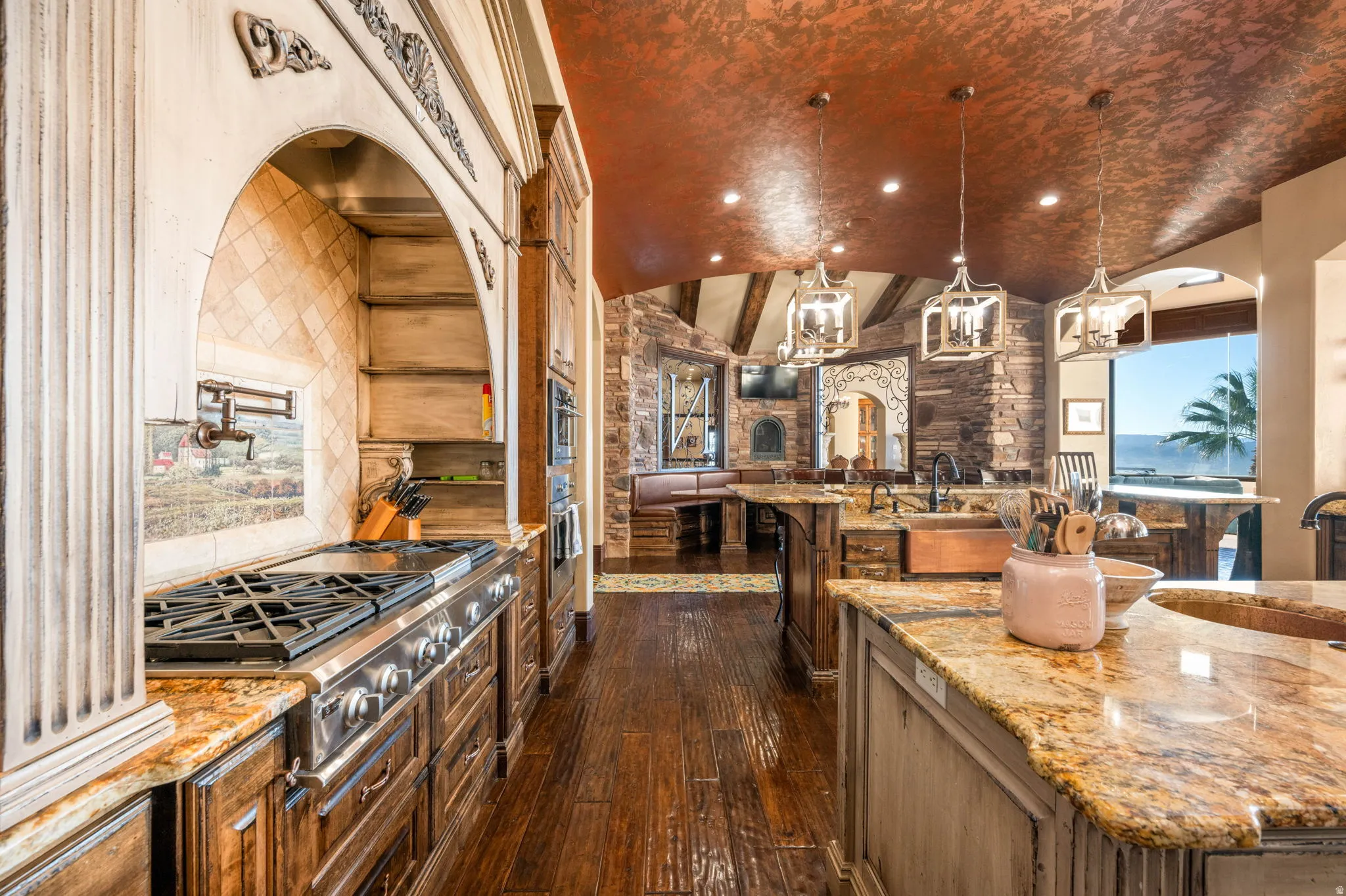 Kitchen featuring light stone counters, vaulted ceiling, dark wood-type flooring, pendant lighting, and appliances with stainless steel finishes