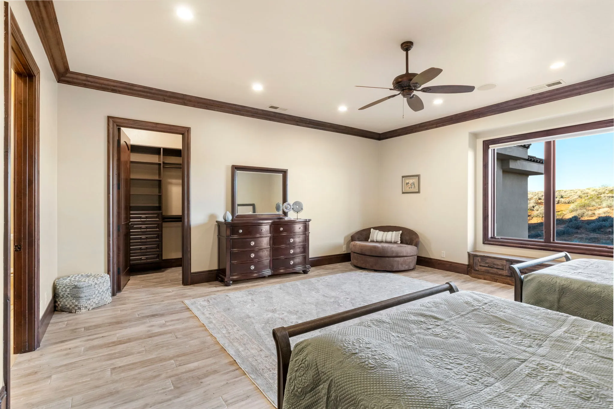 Bedroom with a spacious closet, ornamental molding, recessed lighting, ceiling fan, and light wood finished floors