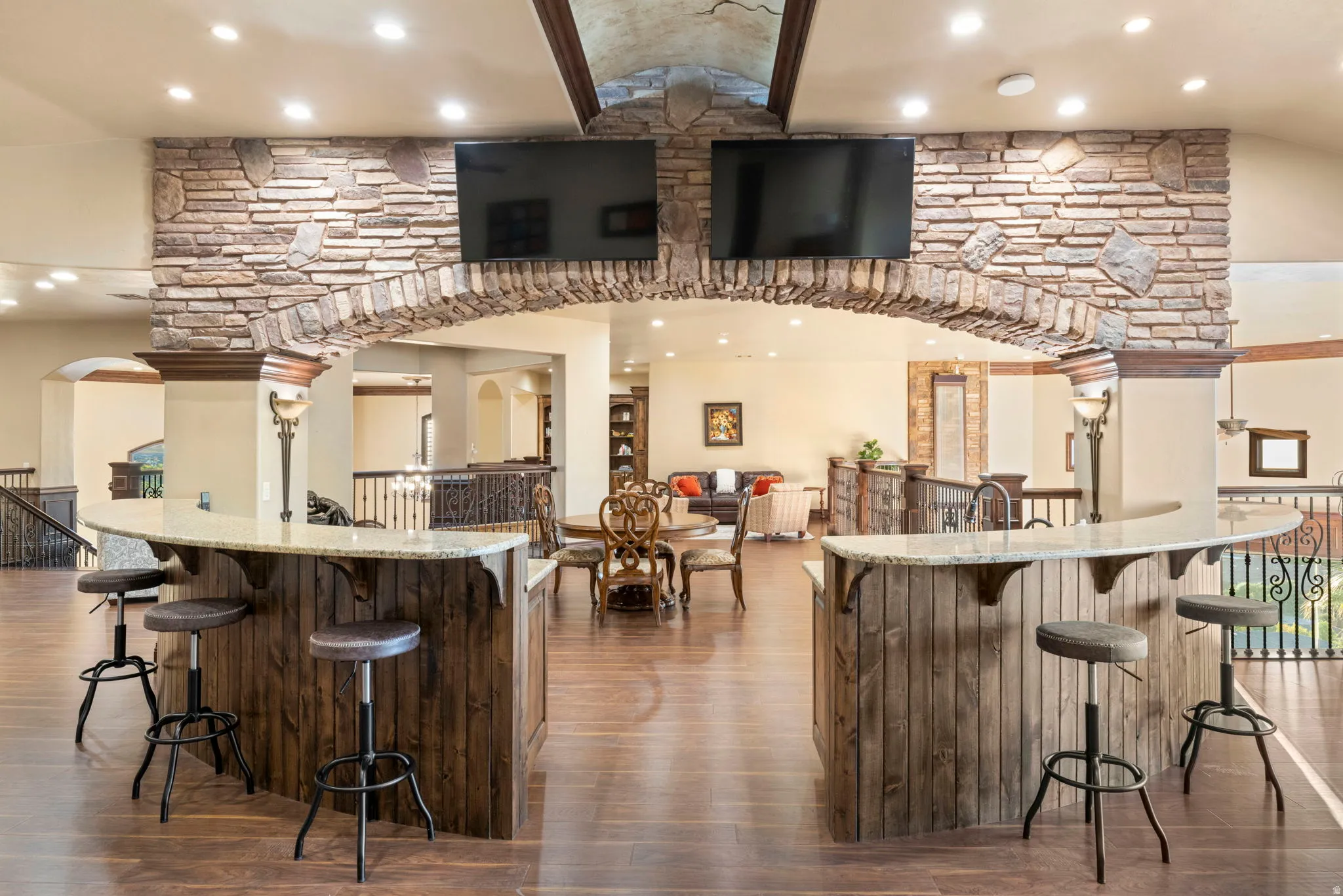 Indoor bar featuring recessed lighting, light stone countertops, dark wood-type flooring, vaulted ceiling, and arched walkways