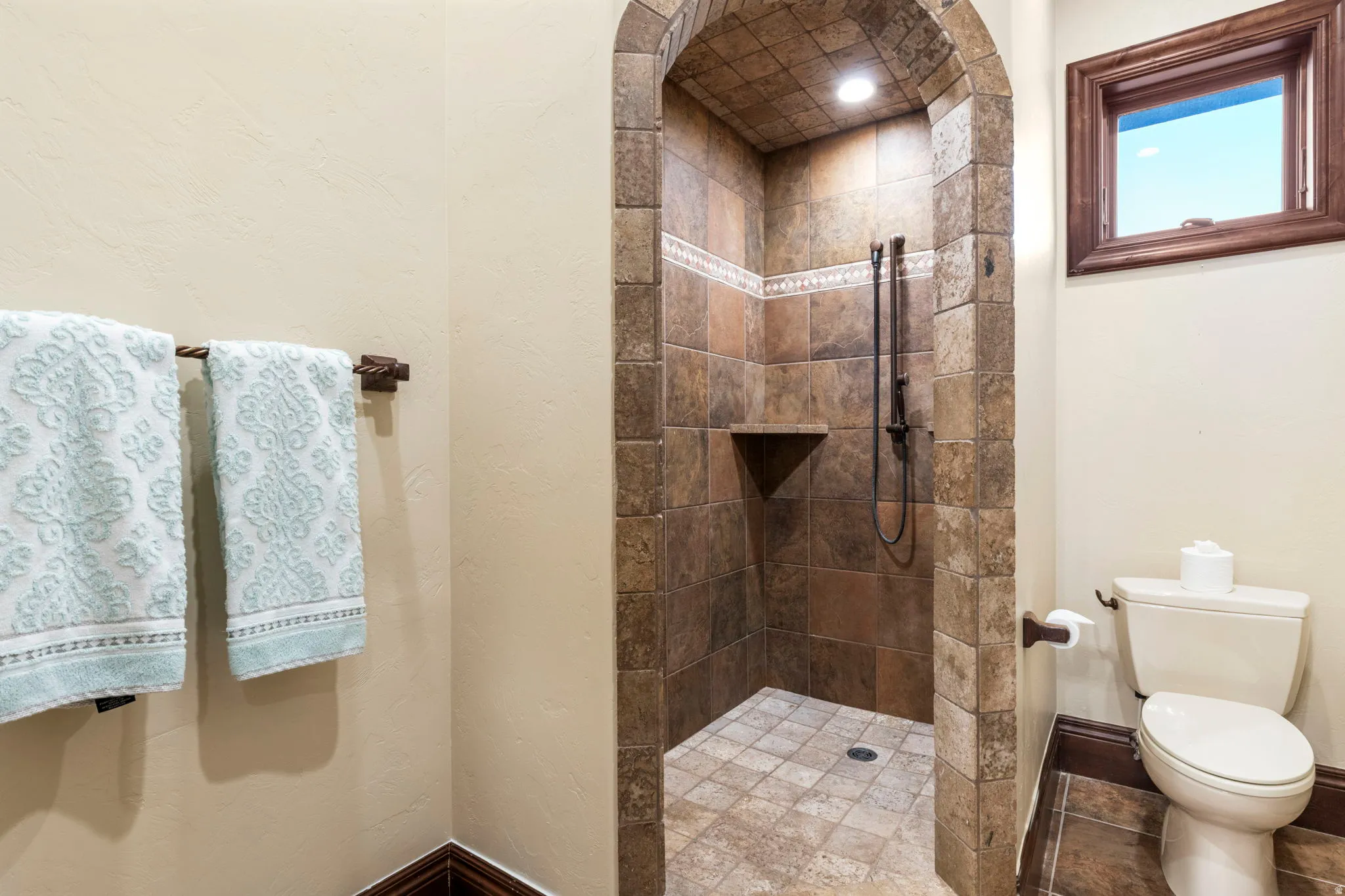 Full bath with tiled shower and a textured wall