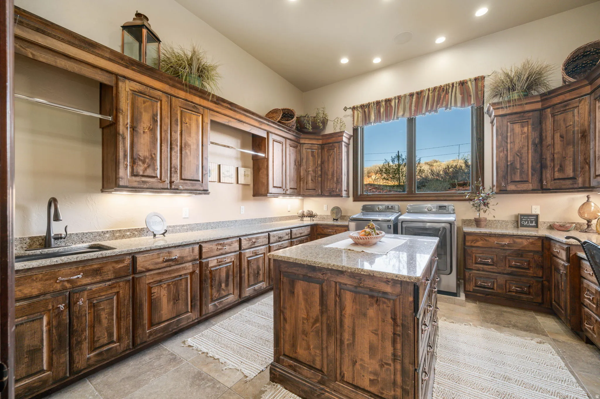 Kitchen featuring light stone counters, a center island, washing machine and dryer, dark brown cabinetry, and recessed lighting