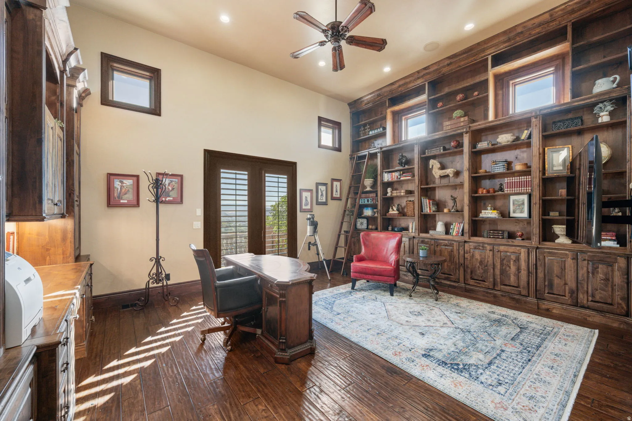 Home office featuring healthy amount of natural light, dark wood-style flooring, a ceiling fan, built in shelves, and recessed lighting