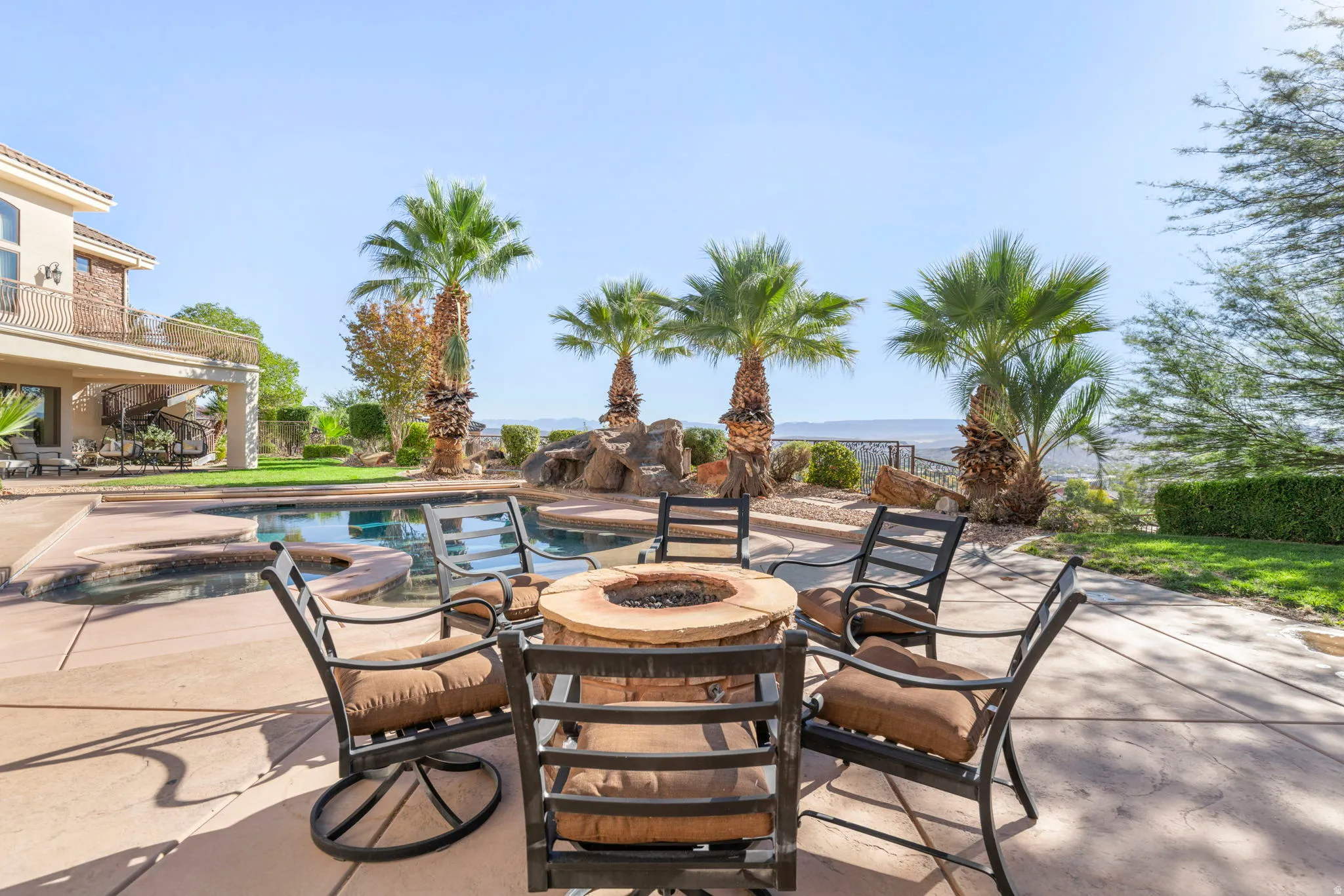 View of patio featuring a fire pit, a water view, and a pool with connected hot tub